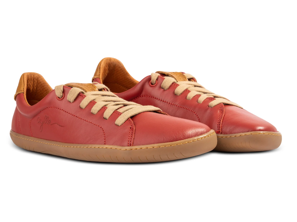 Par røde sneakers med beige snørebånd skråt forfra