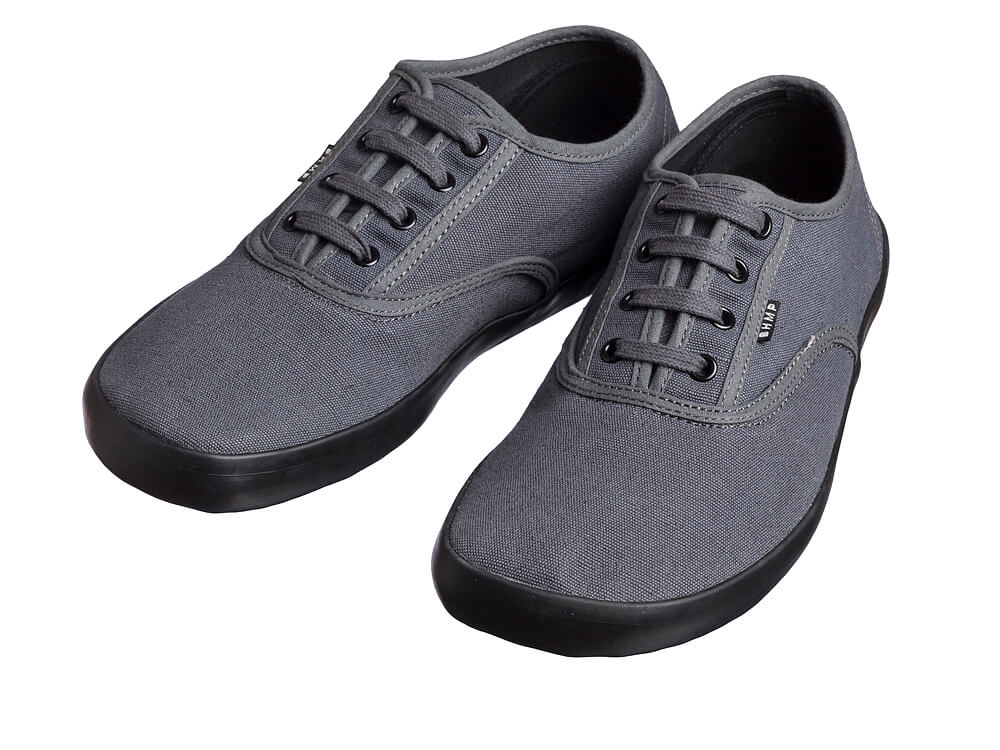 Par grå sneakers skråt forfra med sorte snørehuller og sort sål