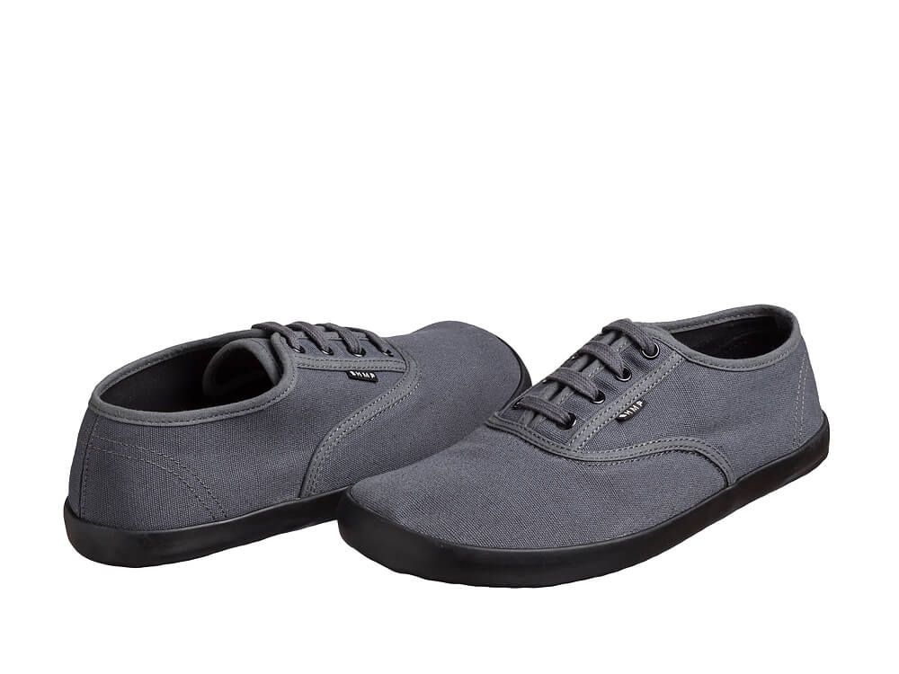 Gråt sneakerpar med den ene sko drejet så hælen vender frem
