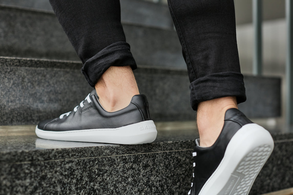 Sorte sneakers i bevægelse op ad mørke stentrin