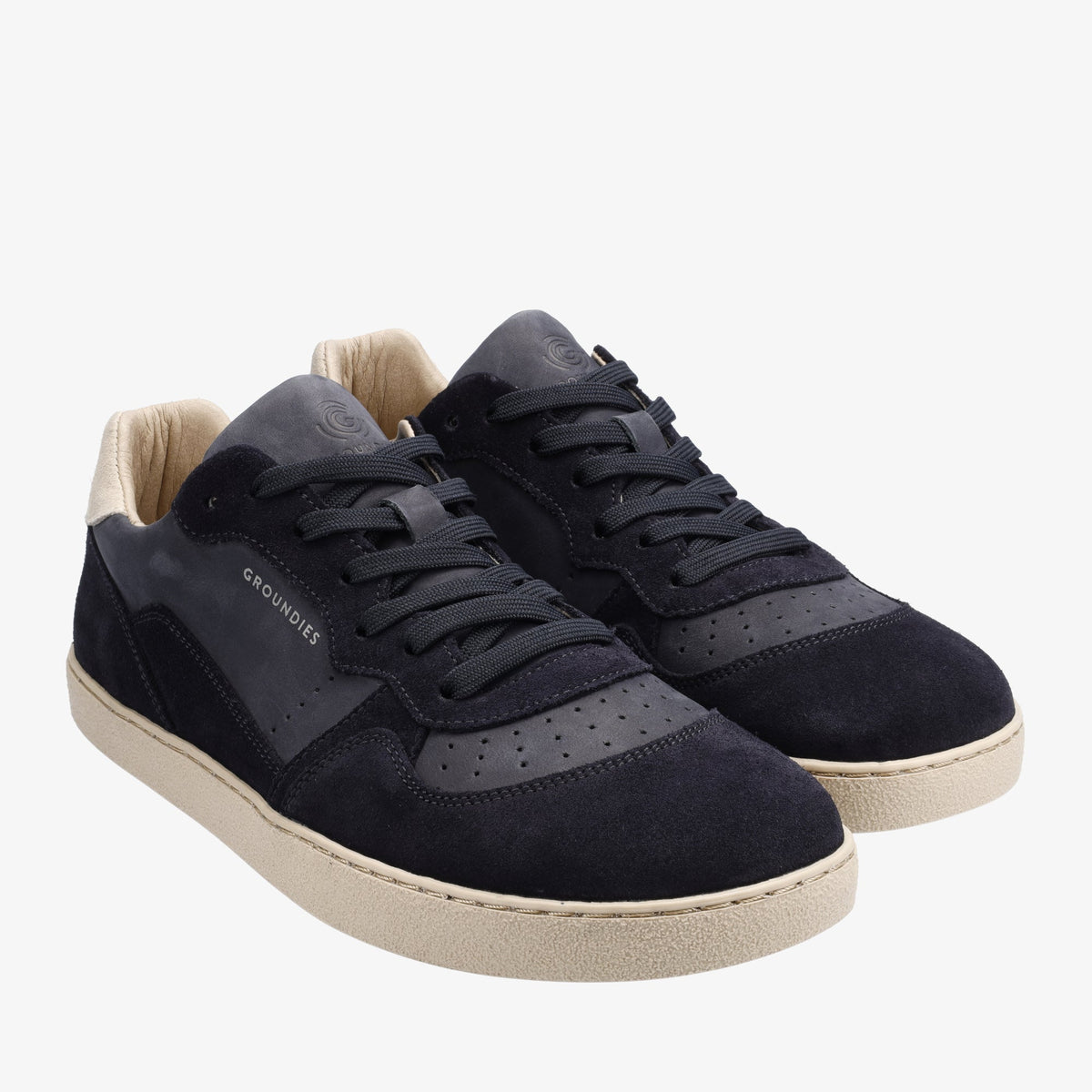Par navy sneakers med lyse såler set skråt forfra