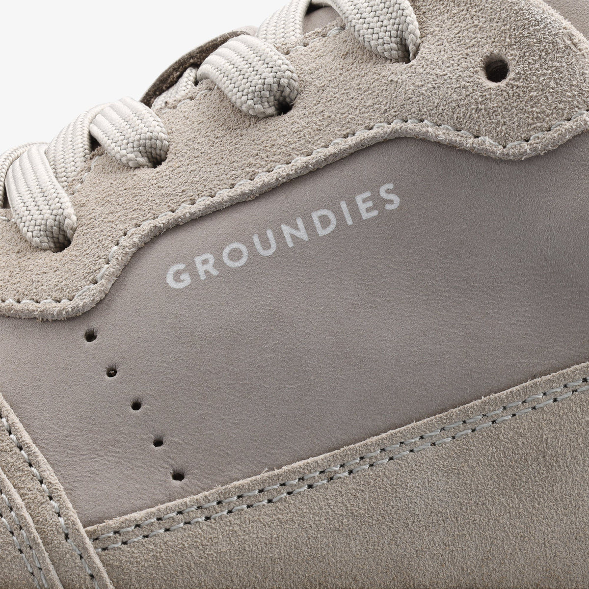 Groundies Nova GS1 barfodssko til kvinder i grå og offwhite ruskind og nubuck, nærbillede af Groundies-logo og perforering