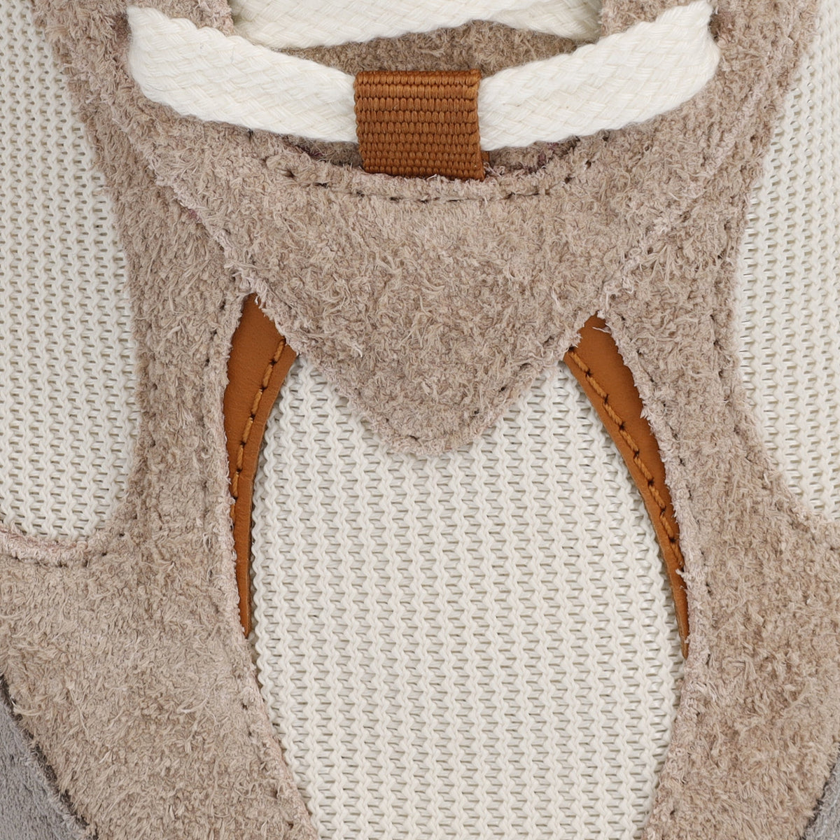 Detalje af beige ruskind, råhvid mesh og karamelfarvet nappalæder med syninger