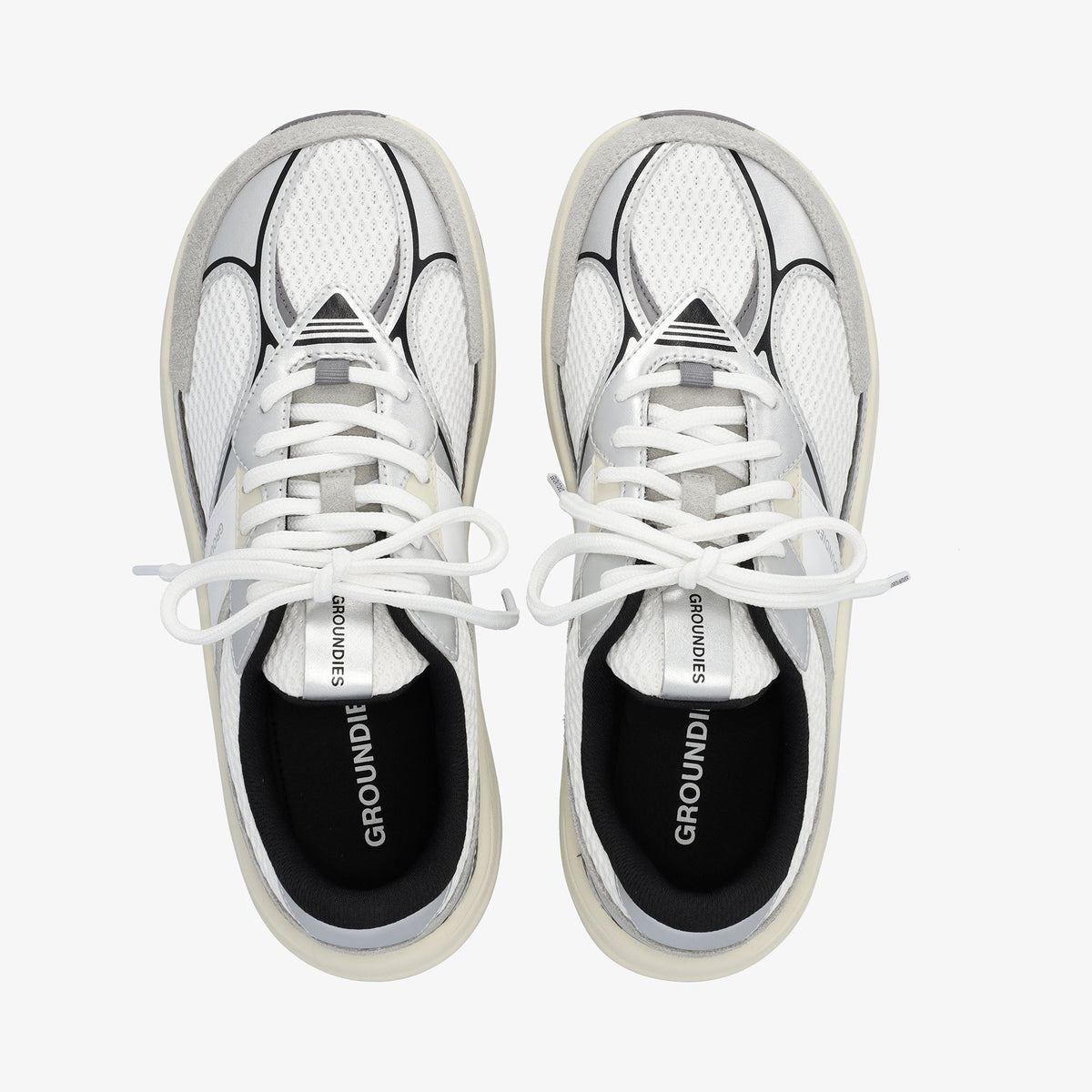 Par hvide sneakers med sølvdetaljer set oppefra med snørebånd