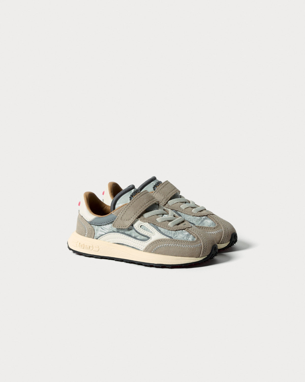 Par sølvfarvede børnesneakers med velcrorem og snørebånd, set skråt forfra