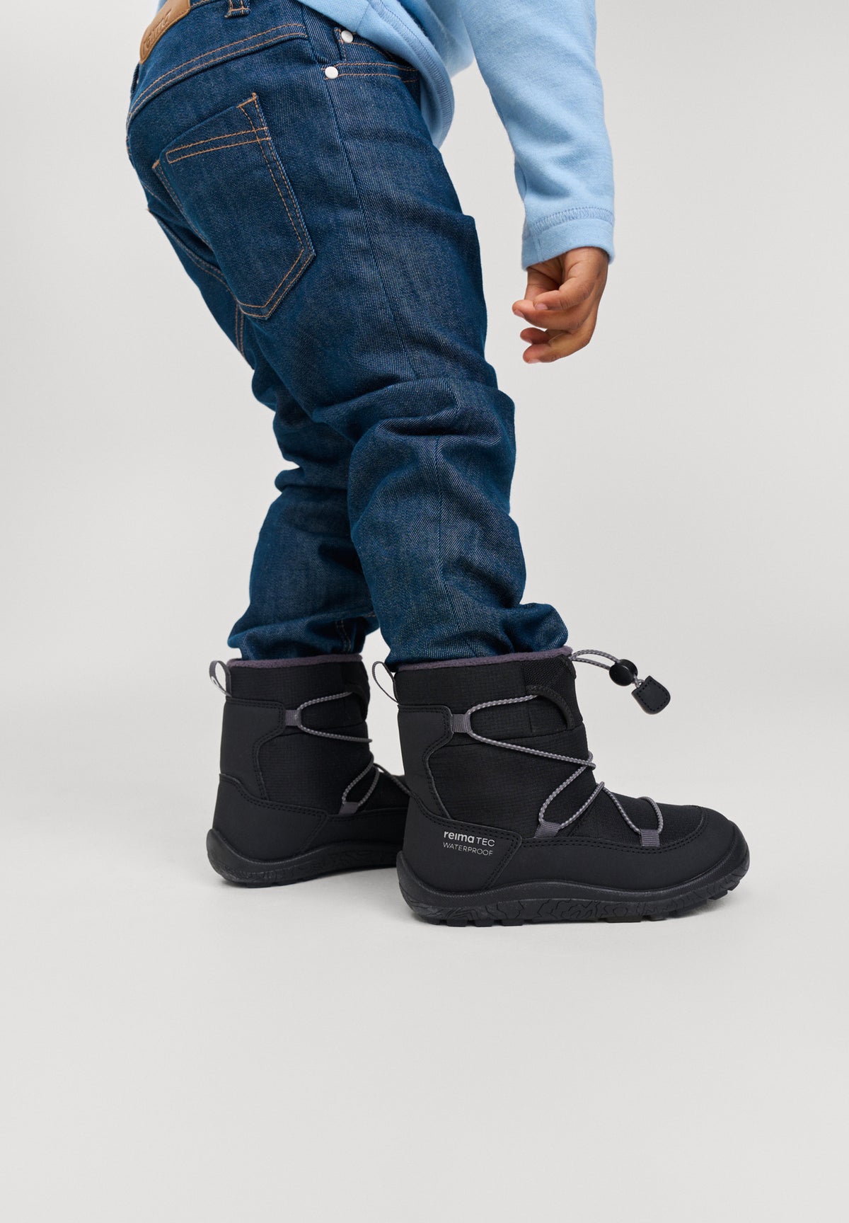 Sorte vinterstøvler på barn i jeans fra siden