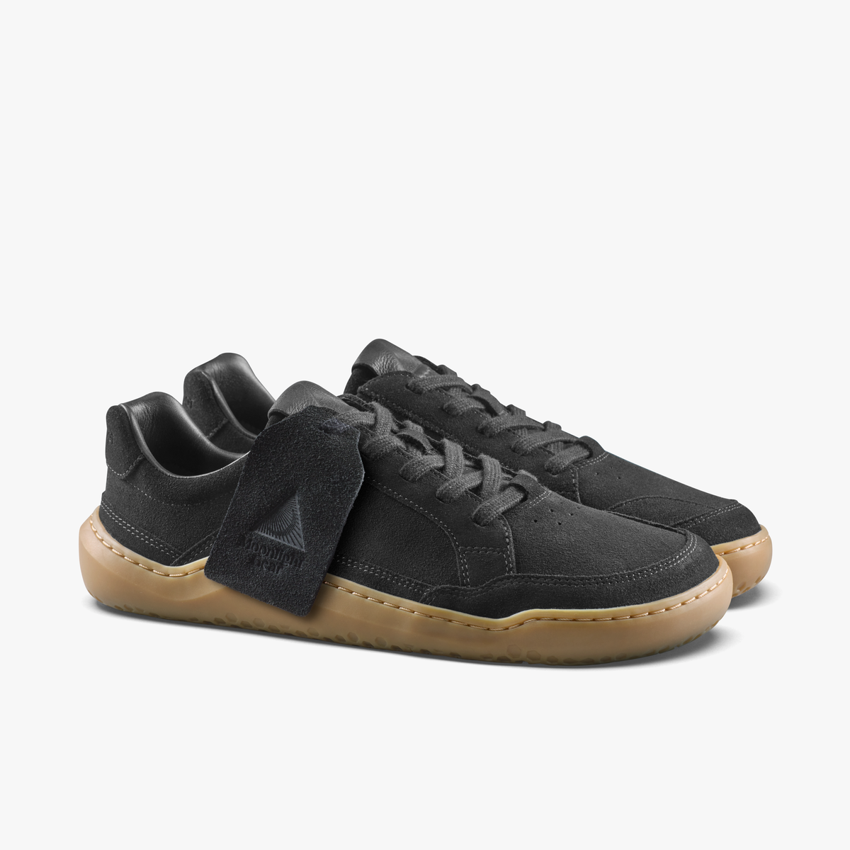 Par sorte sneakers med Moonlight Gear-hængemærke ved snørebåndene set skråt forfra