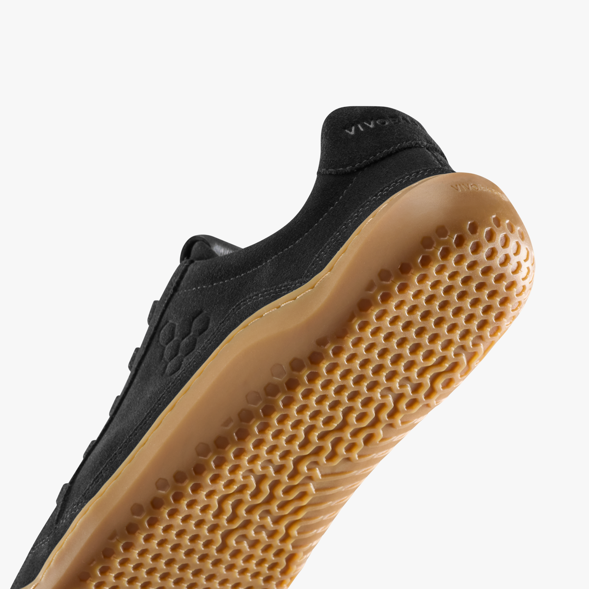 Nærbillede af hælen og gummisålens mønster på sort sneaker
