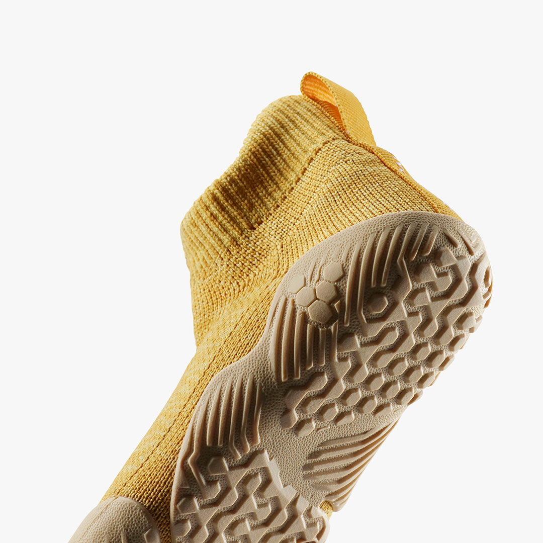 Vivobarefoot Pluma Knit Toddlers sko i Honey Gold. Fleksibel strik, tynd sål med bikube-mønster, ideel til naturlig fodbevægelse. Hælstrop for nem påtagning.