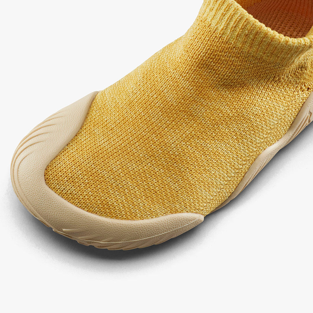 Vivobarefoot Pluma Knit Toddlers sko i Honey Gold med en soklignende, sømløs strikket overdel og en sand beige sål, som giver fleksibilitet og åndbarhed.