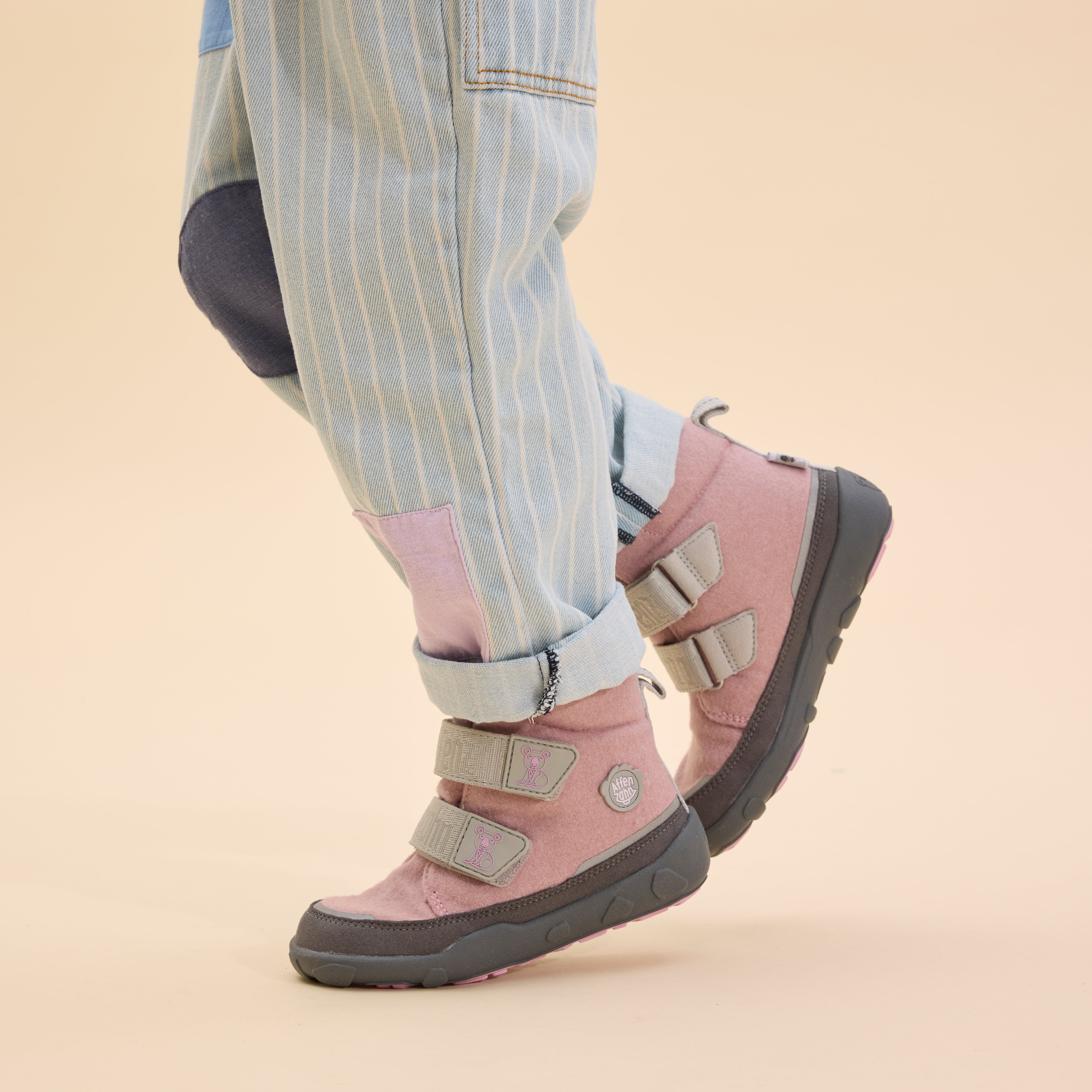 Affenzahn Winter Boot Wool Comfy, variant Koala, in light pink with gray details, worn by a child in rolled jeans. Features Velcro straps and sturdy sole for kids.