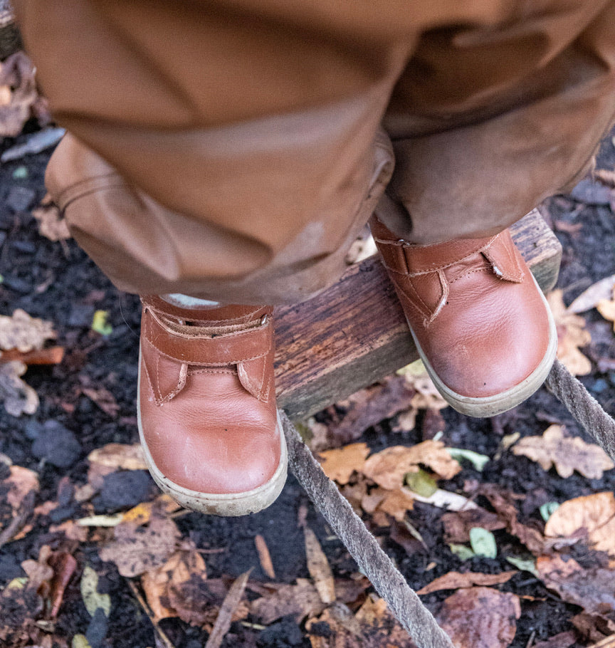 Barn i naturen iført Gogsig Wilson barefoot sko i farven Dark Brown. Skoene har en rund tå og flad sål, ideel til udendørs brug om efteråret.