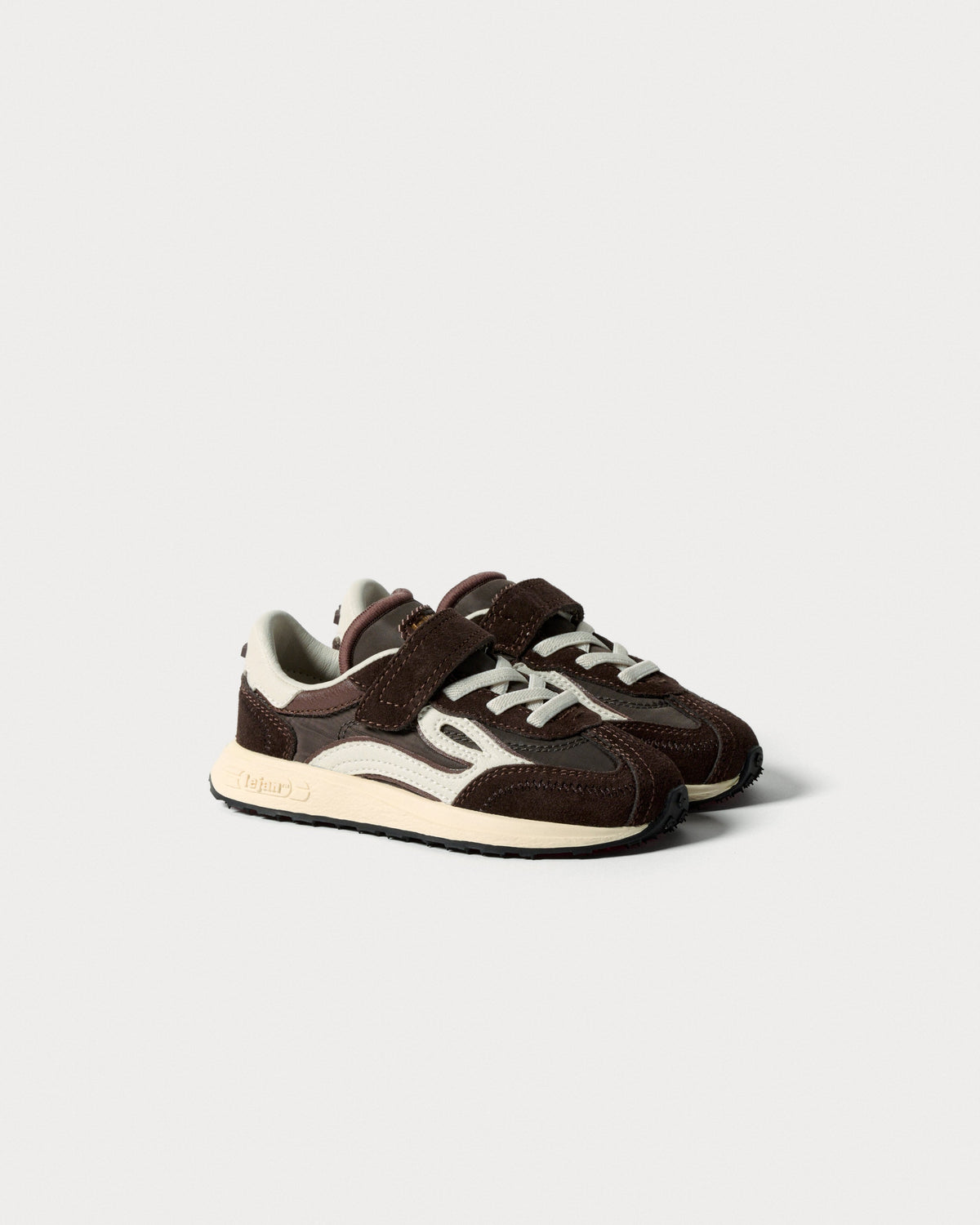 Par brune børnesneakers med velcrorem og snørebånd, set skråt forfra