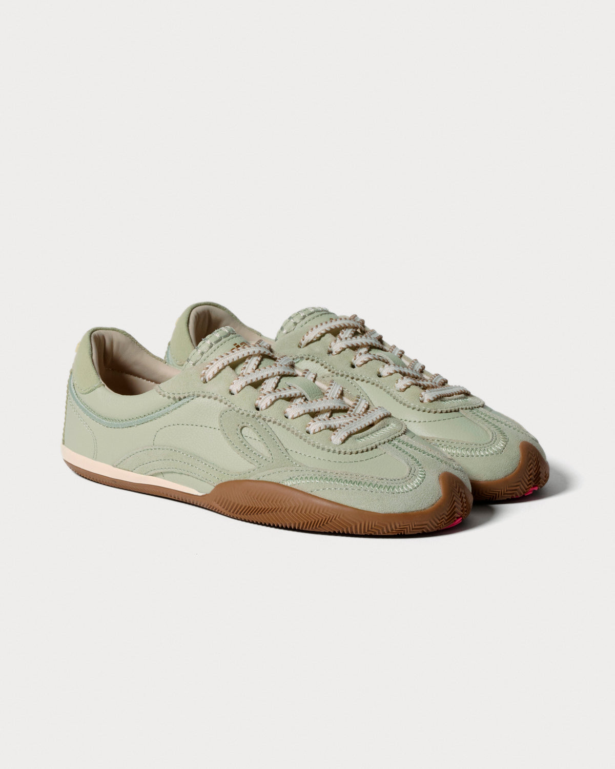 Par mintgrønne sneakers med brun gummisål set skråt forfra