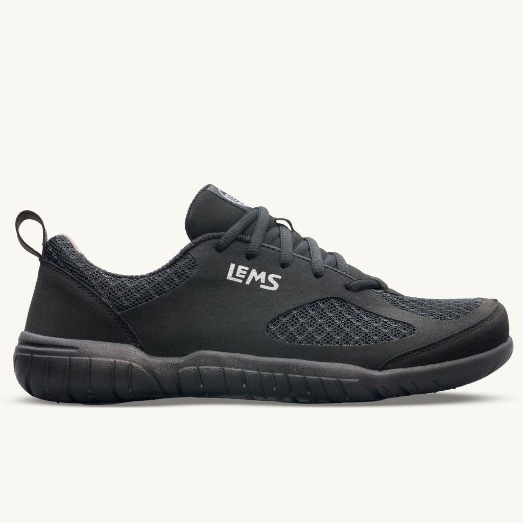 Lems Primal 3 unisex sko i sort, set fra siden. Minimalistisk design med mesh-overdel, flad fleksibel sål, hvidt Lems logo og sort snørebånd. Velegnet til barfodsfølelse.