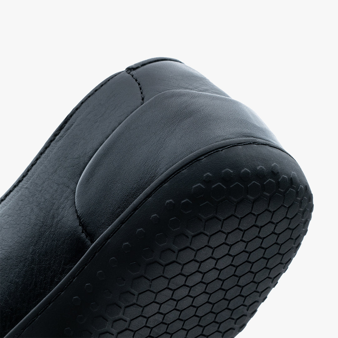 Detaljeret nærbillede af hælen på en Vivobarefoot Ra III Lux Mens sko i varianten Obsidian, med hexagonmønster på sålen for greb og sensorisk feedback. Minimalistisk design.