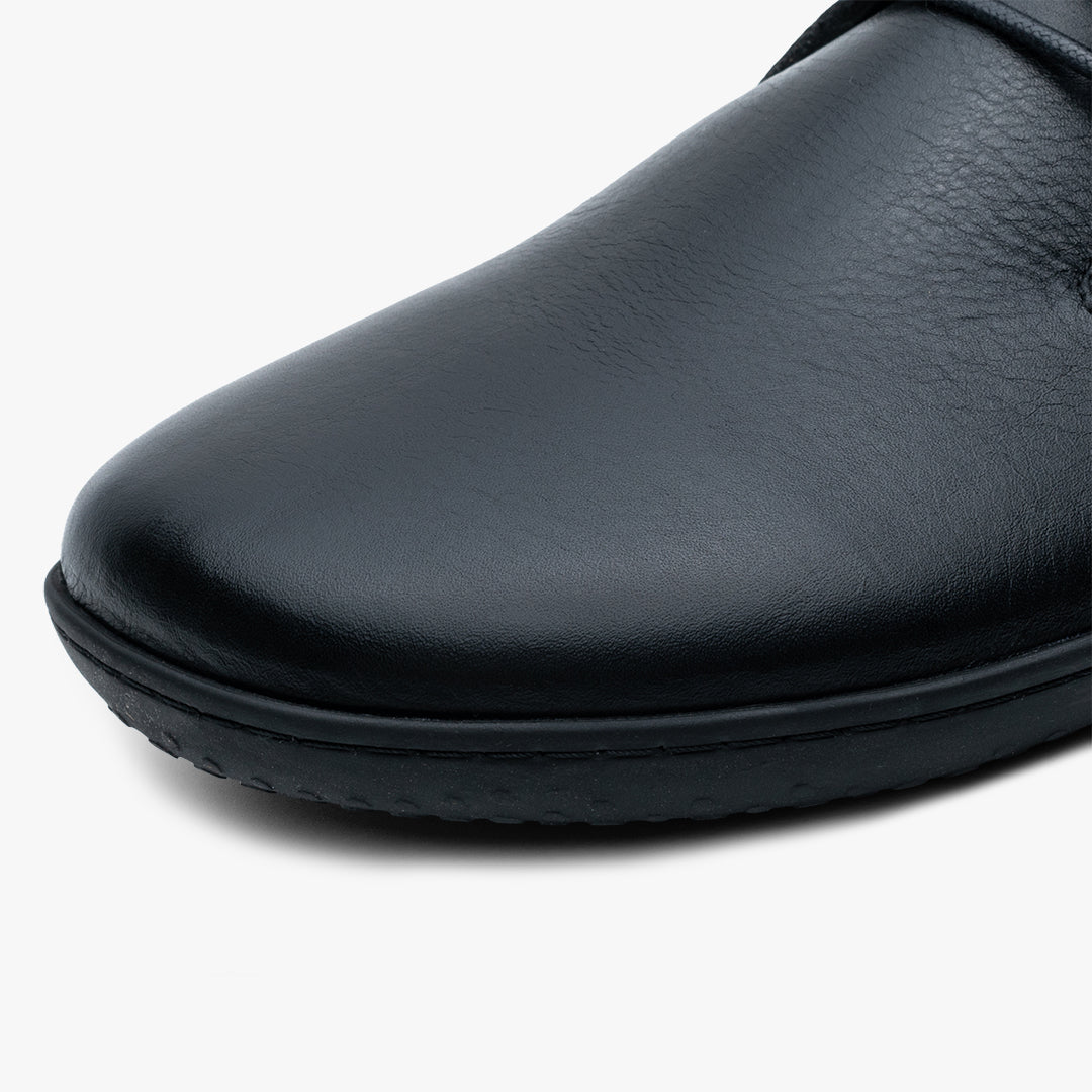 Vivobarefoot Ra III Lux Mens sko i varianten Obsidian. Nærbillede af rund tå og glat sort læder med let tekstur, der fremhæver minimalistisk design. Naturtro barfodsål.