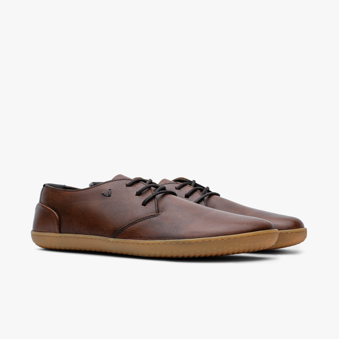 Vivobarefoot Ra III Lux Mens barefoot shoes in Tan, showing a pair at an angled view. Oxford style with leather upper, black laces, and gum rubber outsole.